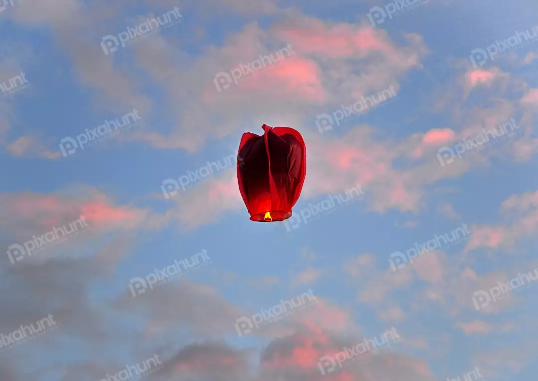 Floating Red Sky Lantern Against Dramatic Sunset Clouds and Blue Sky