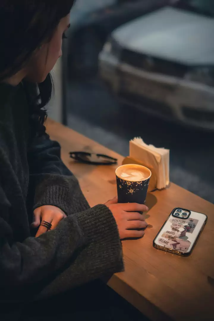 Free Premium Stock Photos Young Woman Sips Winter Latte, Travel Phone on Cafe's Wooden Table with City View