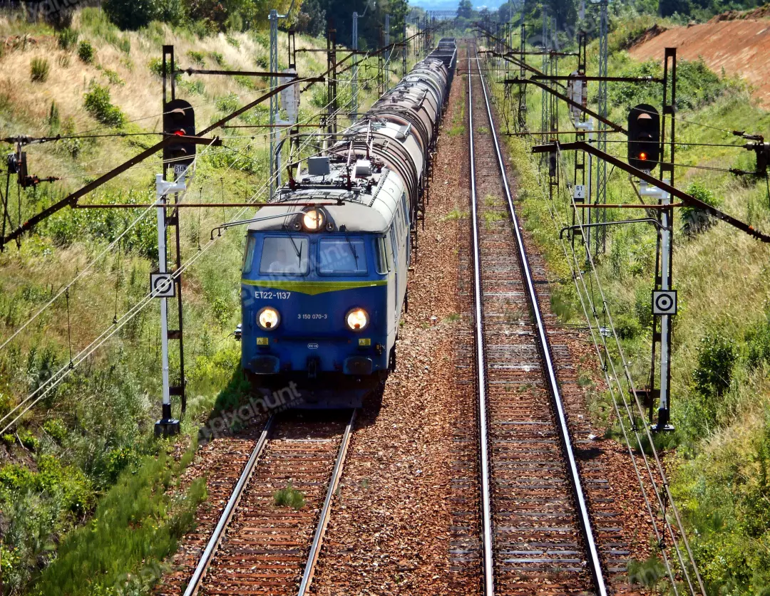 Powerful blue freight train on parallel railway tracks in a vibrant rural landscape