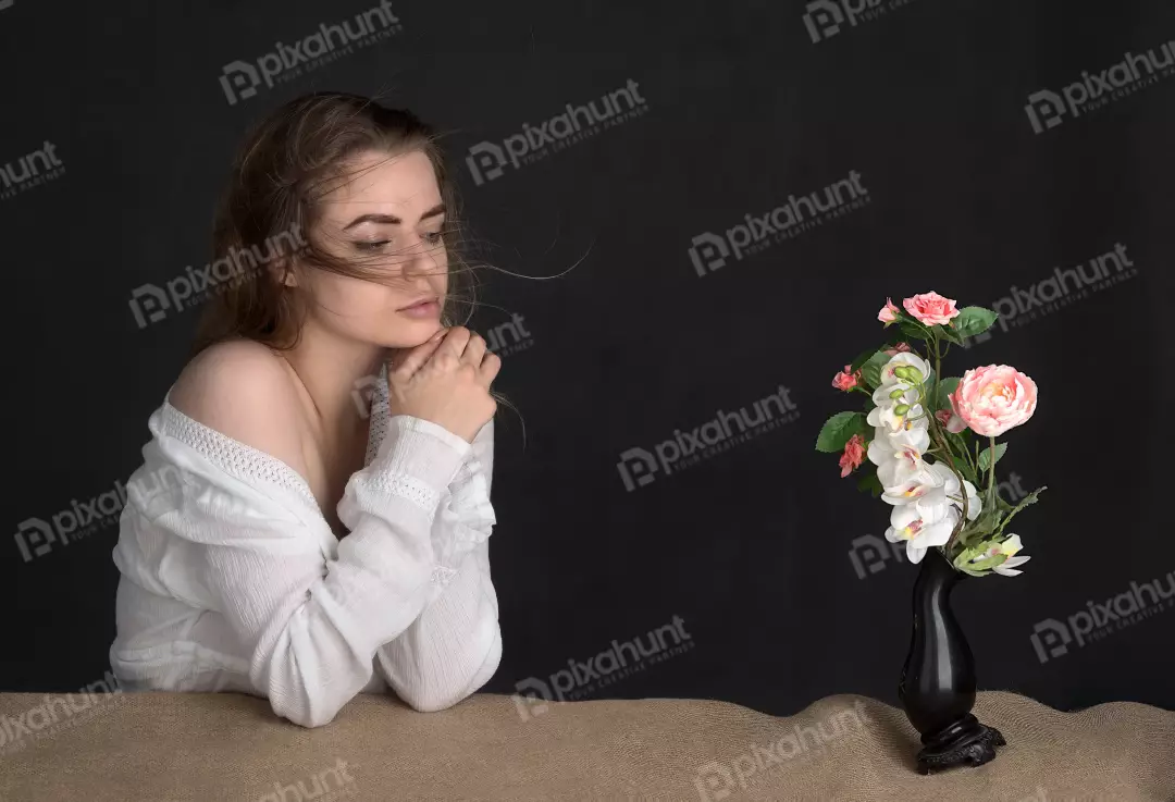 Pensive Young Woman in White Blouse with Clasped Hands and Windswept Hair