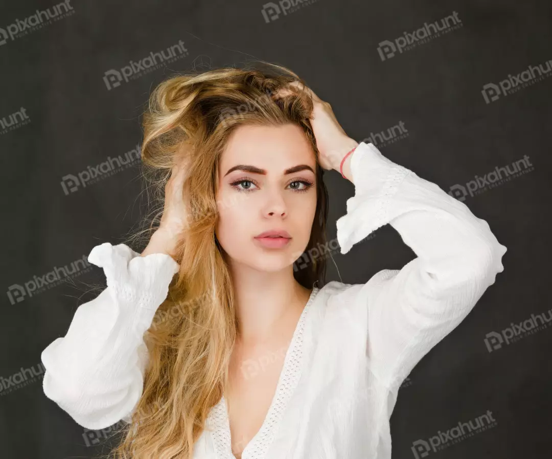 Blonde Woman with Wavy Hair and Hands in Hair Posing on Dark Background