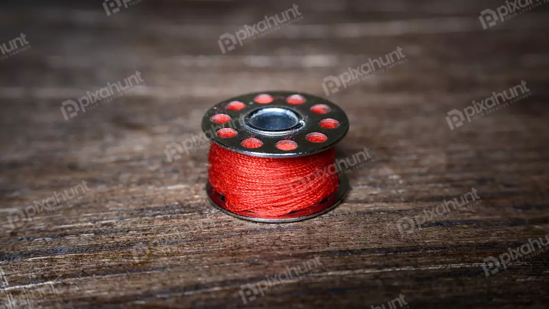 Vibrant Red Thread Bobbin on Rustic Wooden Table