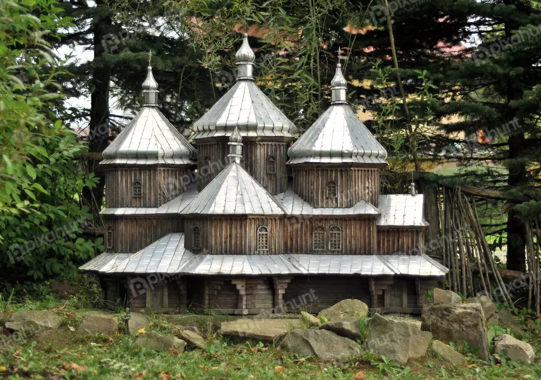 Intricate Miniature Wooden Church Model with Silver Domes Amidst Lush Green Foliage