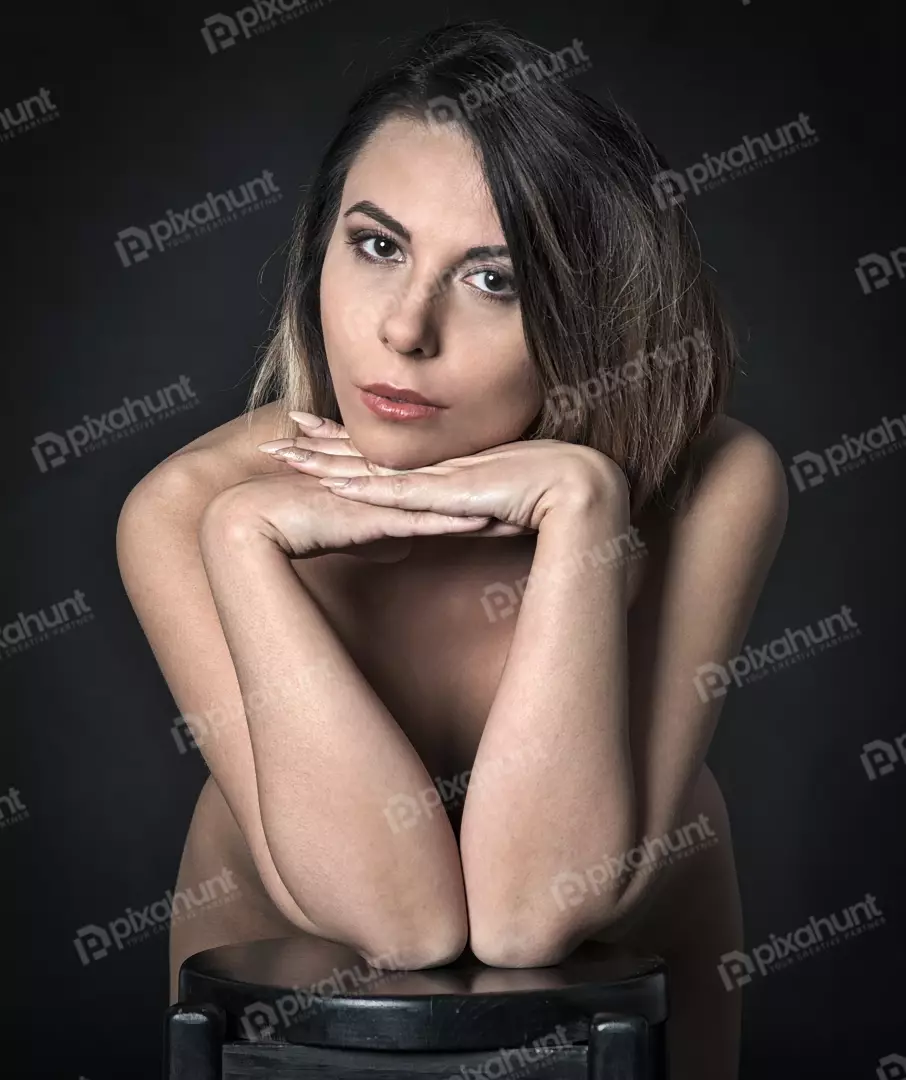 Intense Portrait of Young Woman with Direct Gaze and Bare Shoulders on Dark Background