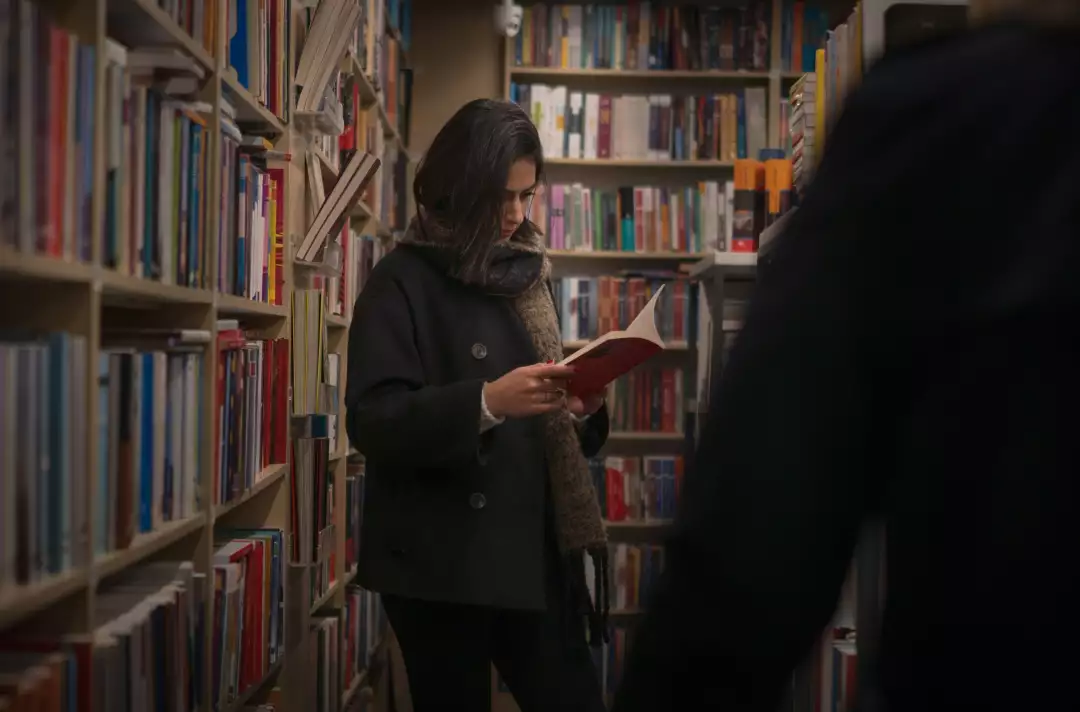 Free Premium Stock Photos Young woman reading a book in a bookstore aisle filled with shelves of books