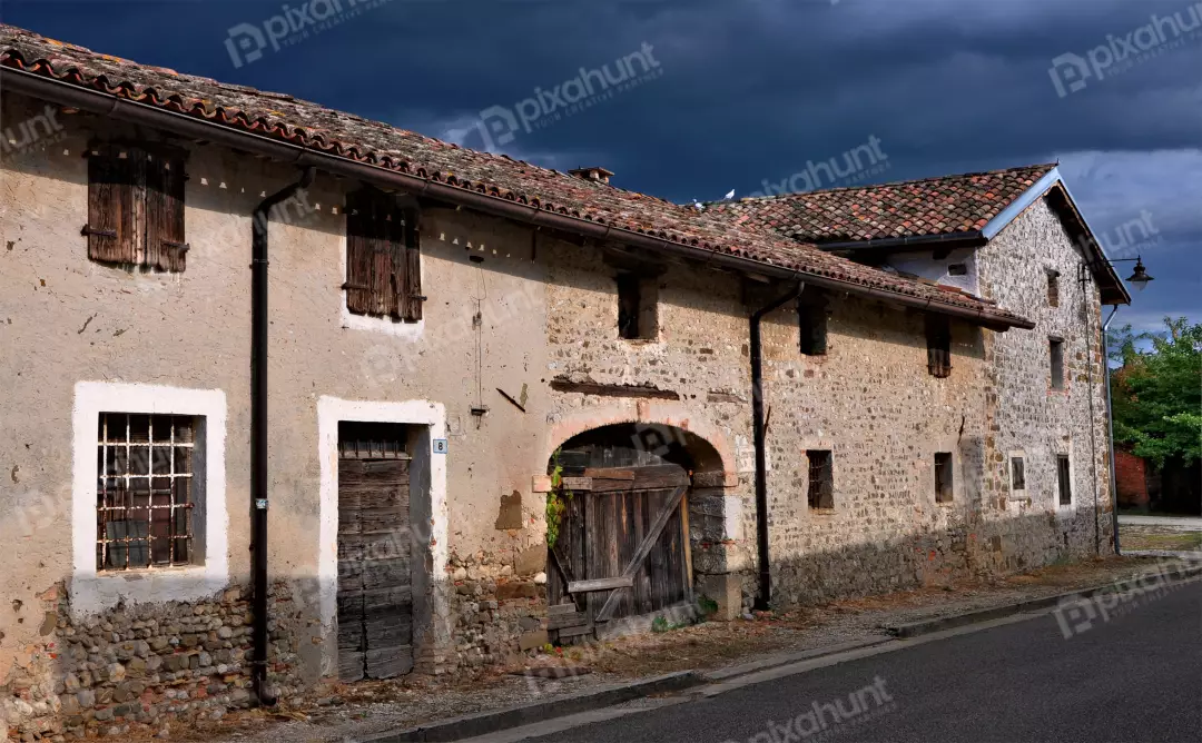 Old Rustic Stone Farmhouse with Terracotta Roof Tiles Under Stormy Sky