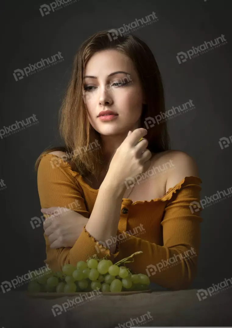 Pensive Young Woman in Mustard Off-Shoulder Top with Fresh Green Grapes