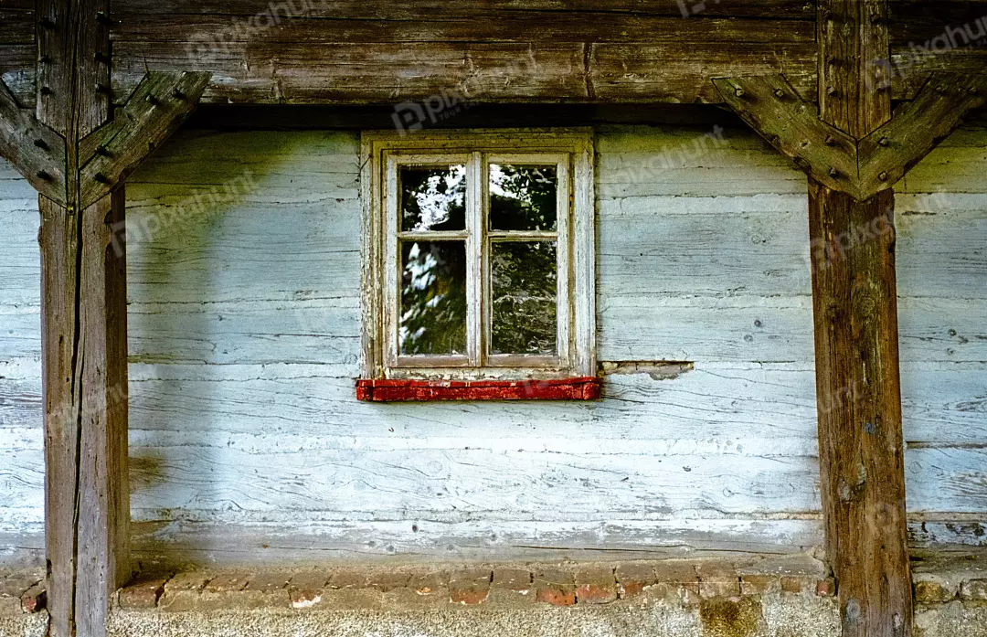 Weathered Wooden Wall with a Distressed Window Frame on a Rustic Building Facade