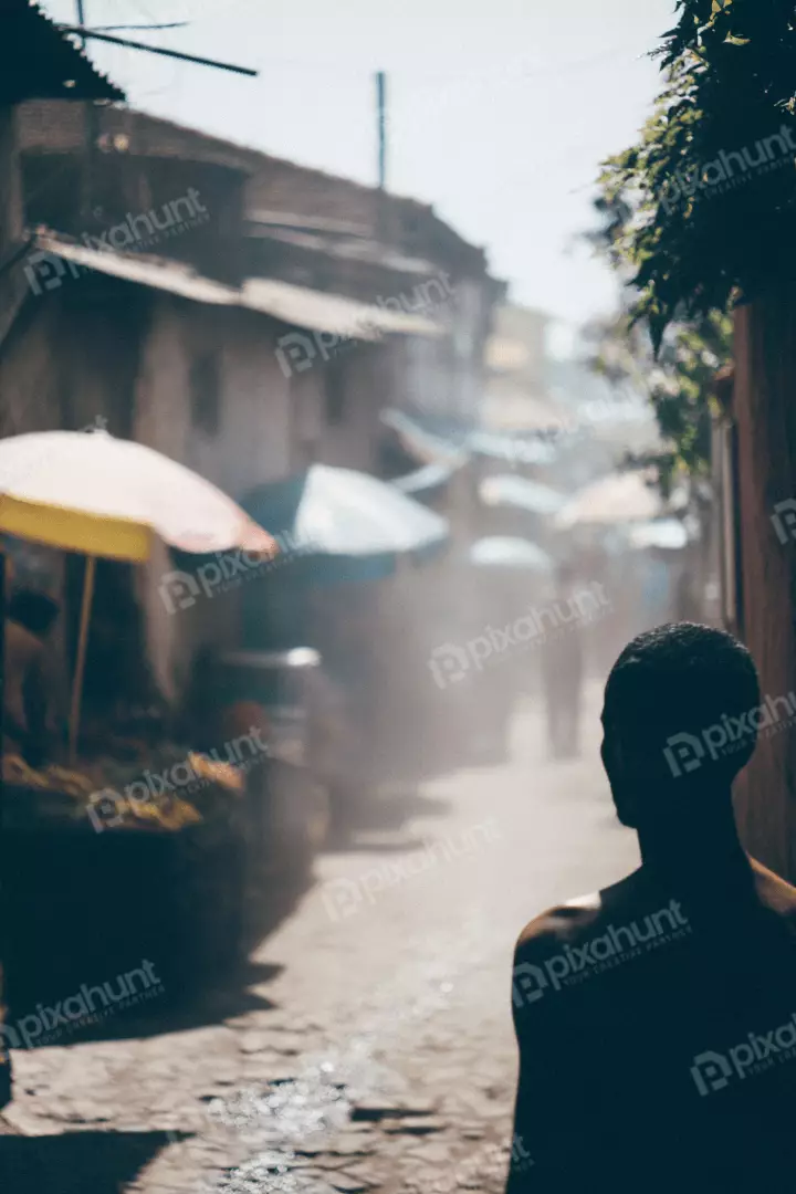 Free Premium Stock Photos Silhouette of a man walking through a dusty market street with stalls and umbrellas