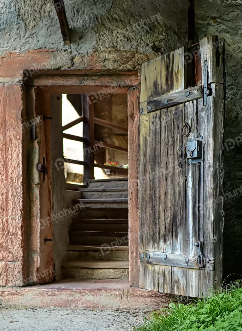 Rustic Stone Building Entrance with Open Wooden Door and Interior Staircase