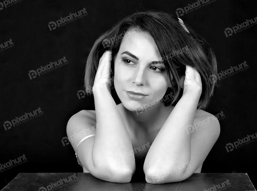 Elegant Black and White Portrait of Young Woman with Reflective Gaze and Hands Near Head