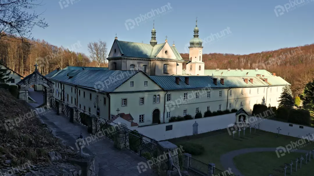 Historic European Monastery Complex with Green Roofs, Bell Tower, and Stone Archway