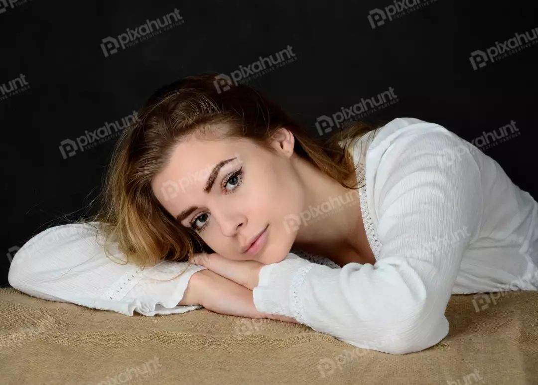 Serene Young Woman with Blonde Hair Resting Head on Arms Studio Portrait