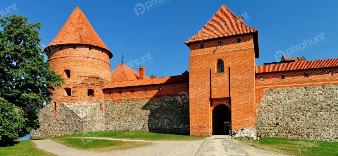 Historic Brick Castle Walls and Terracotta Roofs under Blue Sky