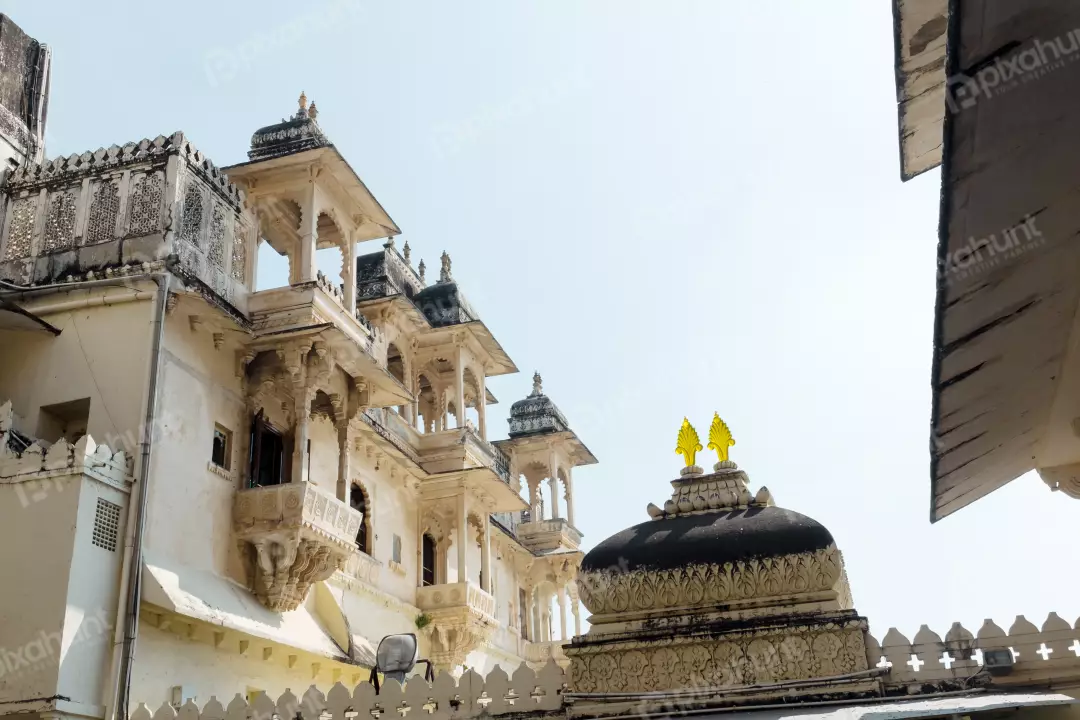 Historic Indian Palace Architecture with Ornate Balconies and Intricate Carvings Against Clear Sky