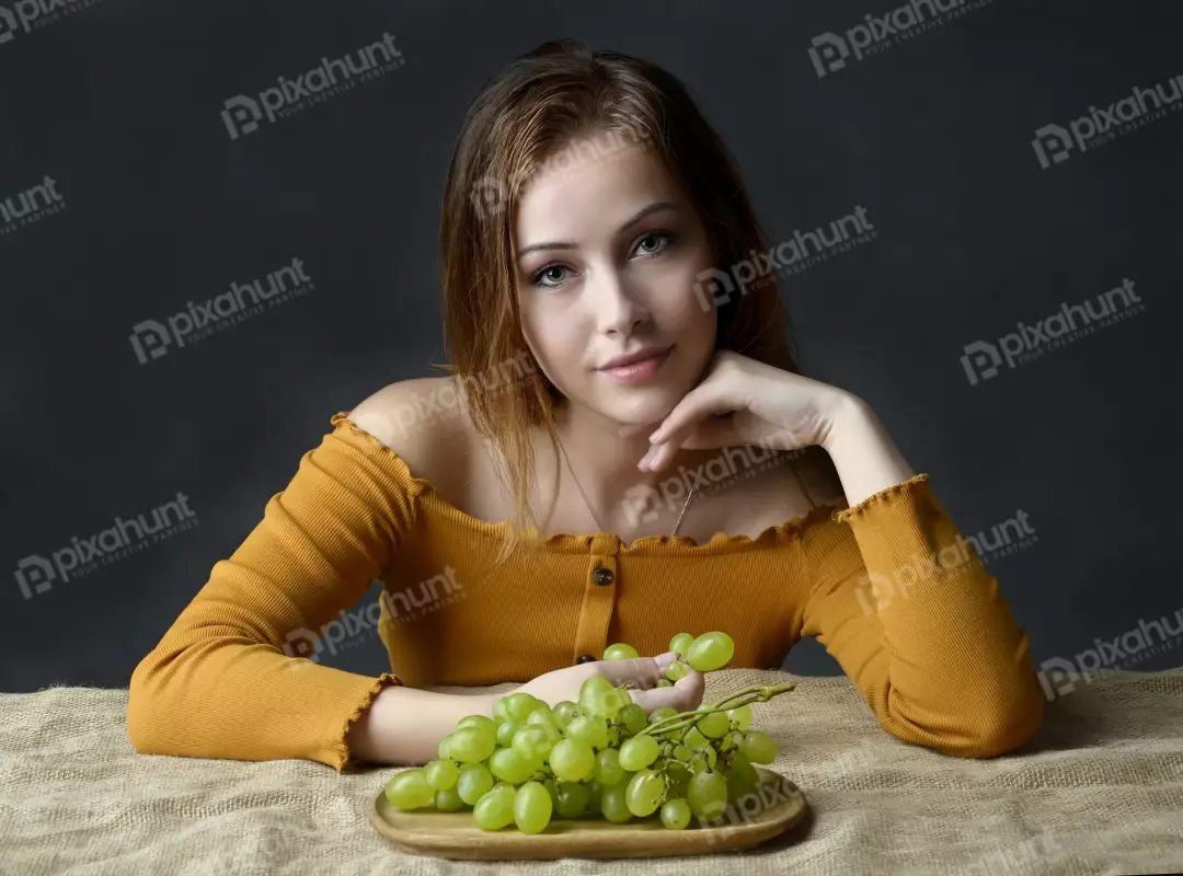 Captivating Young Woman in Off-Shoulder Top with Fresh Green Grapes