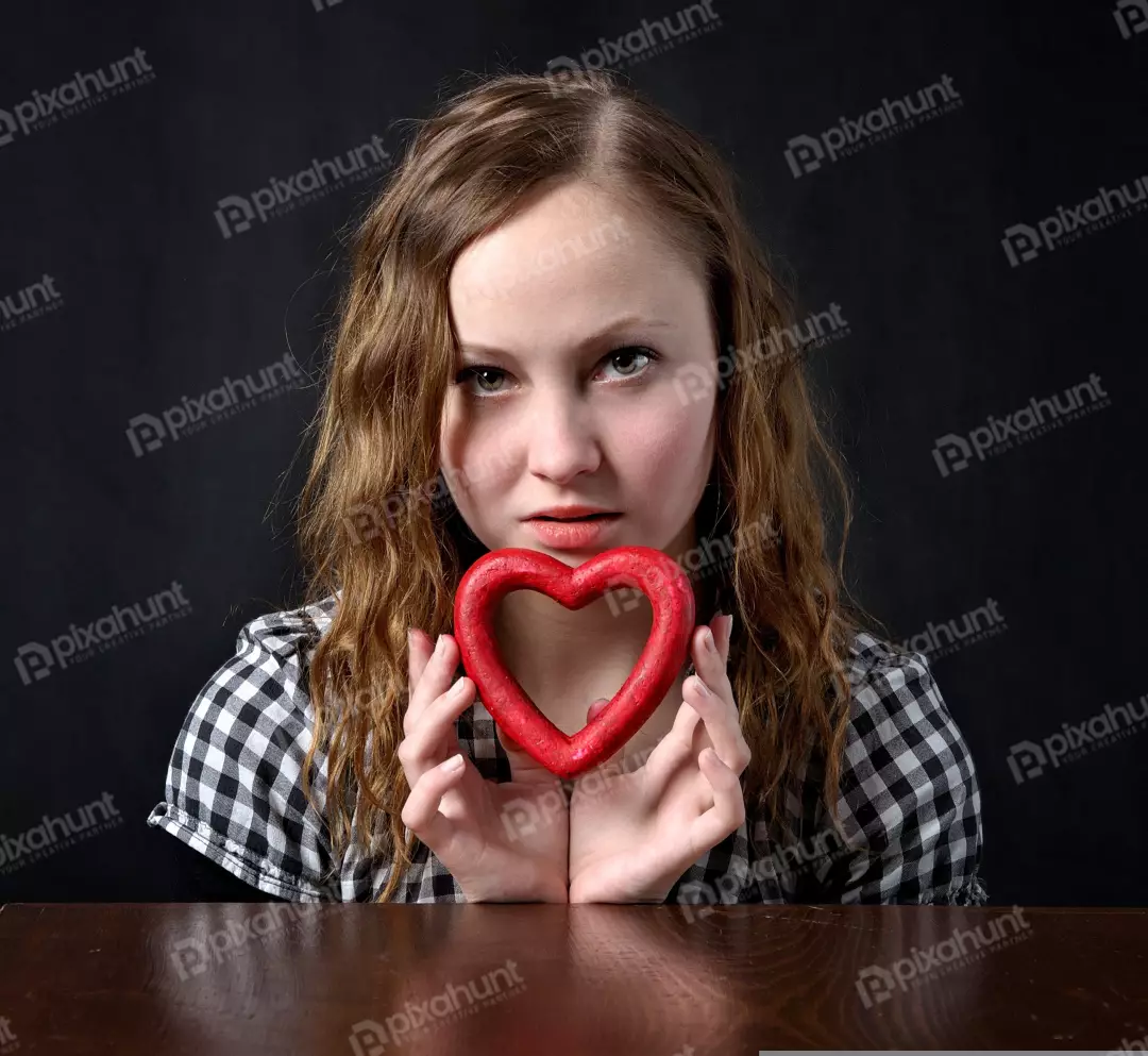 Young Woman with Intense Gaze Holding Red Heart Symbolizing Love and Affection