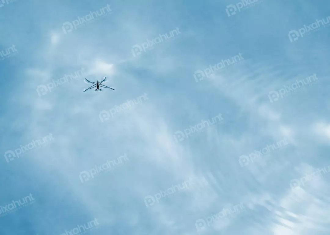 Minimalist lightweight drone flying in clear sky with soft clouds and reflection