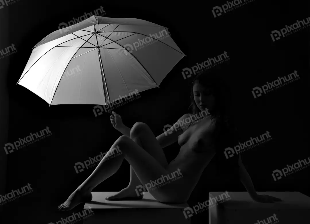 Nude Woman Posing Gracefully with White Umbrella in Dramatic Black and White Studio Light