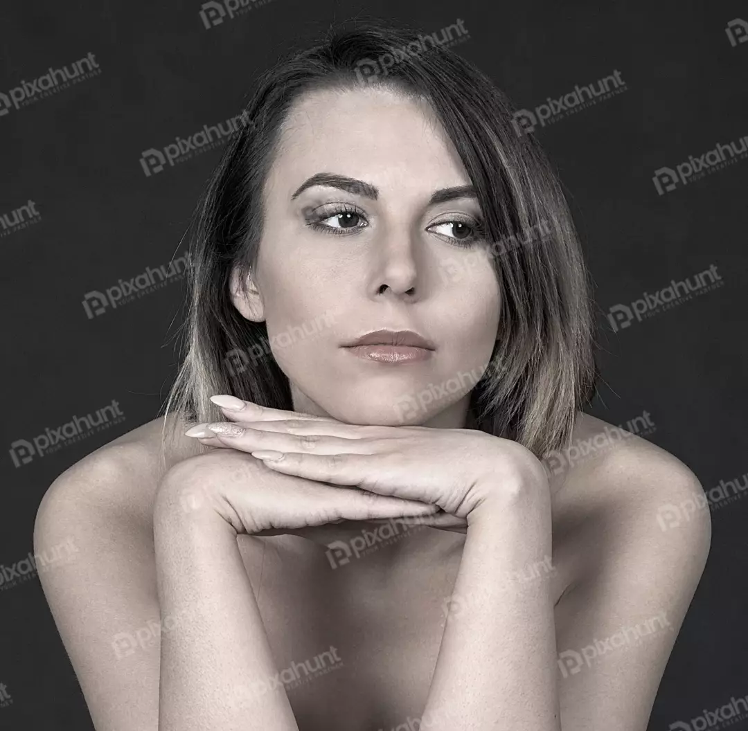 Pensive woman with expressive eyes resting chin on crossed hands monochrome portrait