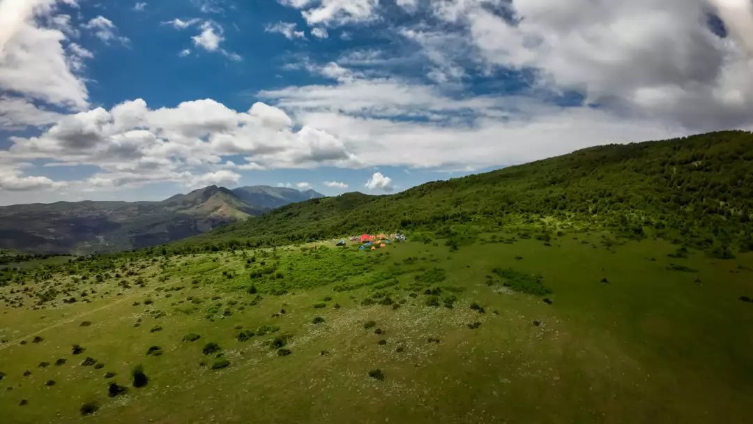 Free Premium Stock Photos Drone view of a campsite with tents and vehicles on a grassy mountain slope under a cloudy sky