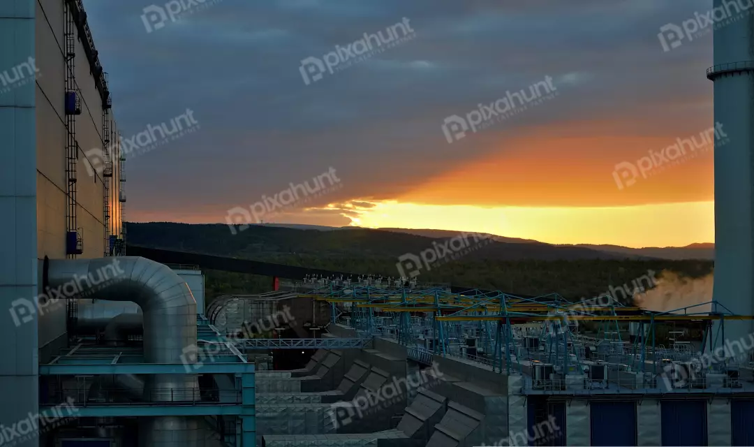 Industrial Power Plant and Green Mountains at Sunset