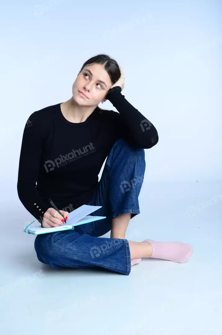 Pensive Young Woman Writing Notes in Notebook on White Background