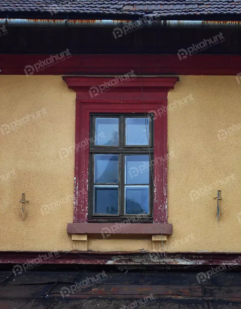 Weathered architectural facade of an old building with a rustic window and peeling paint