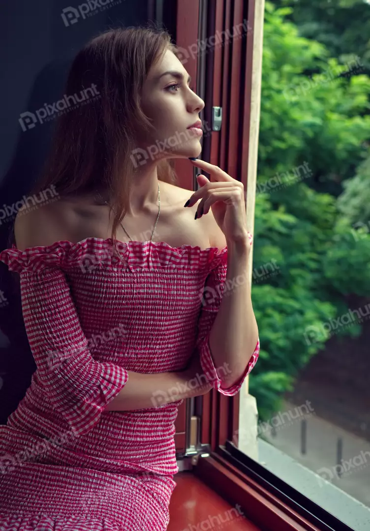 Pensive Woman in Off-Shoulder Gingham Dress Gazing Thoughtfully Out Window