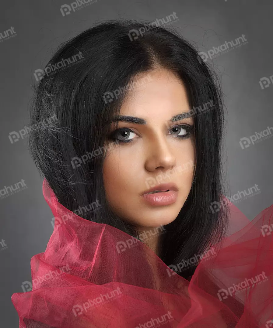 Dramatic Portrait of a Young Woman with Dark Hair Wrapped in Sheer Red Fabric