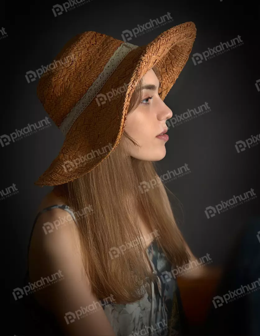 Thoughtful Young Woman in Profile with Straw Hat and Summer Dress