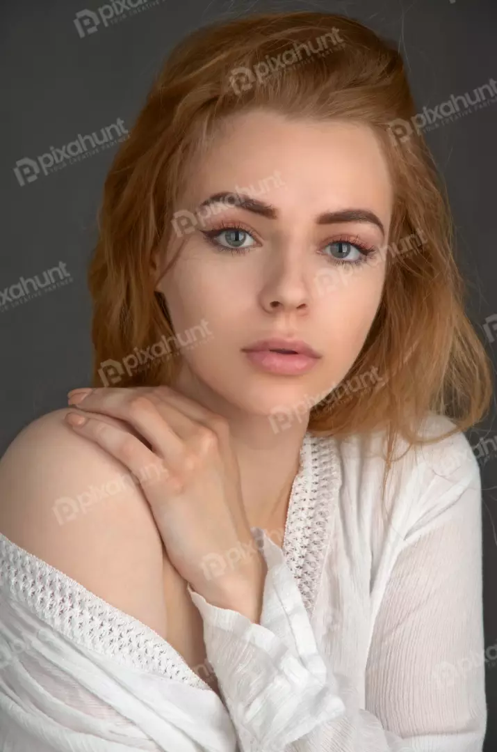 Pensive Young Woman with Reddish Blonde Hair Posing in White Top