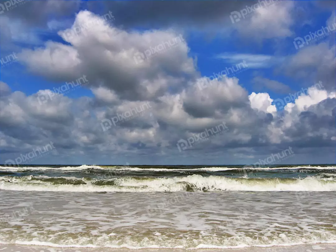 Dynamic Ocean Waves Crashing on Sandy Shore Under Dramatic Cloudscape