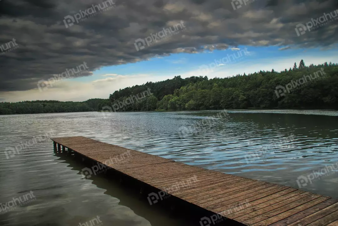 Rustic Wooden Pier on a Tranquil Lake Under Dramatic Cloudy Sky and Forest