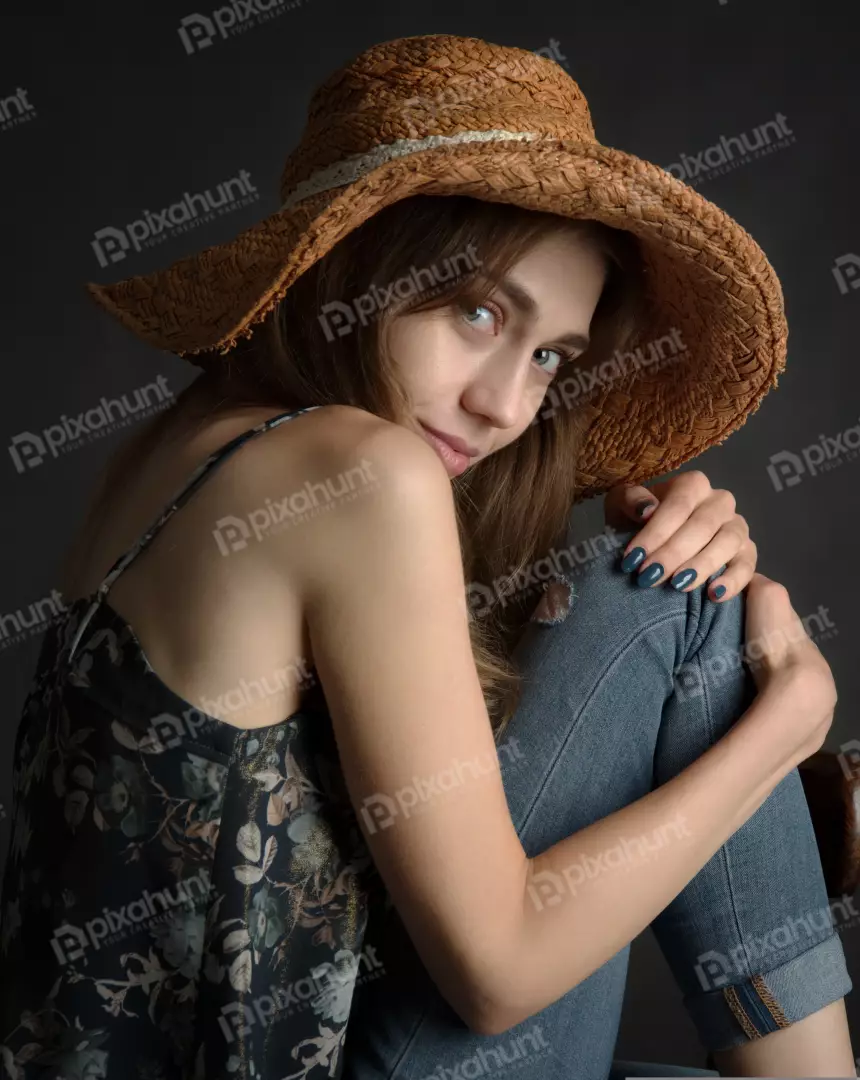 Stylish Young Woman in Straw Hat with Pensive Gaze
