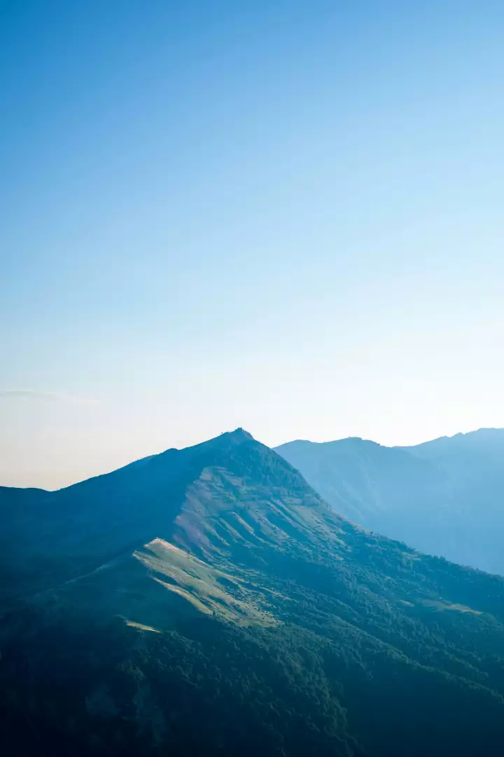 Free Premium Stock Photos Serene mountain landscape with a clear blue sky and lush green slopes