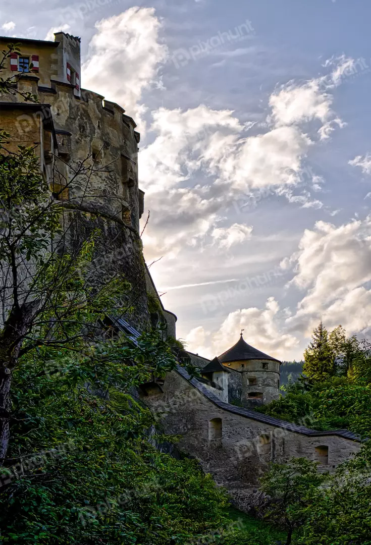 Historic Stone Castle Tower with Red Shutters and Dramatic Cloudy Sky