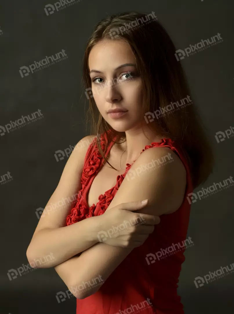 Expressive Woman in Red Top with Crossed Arms and Contemplative Gaze