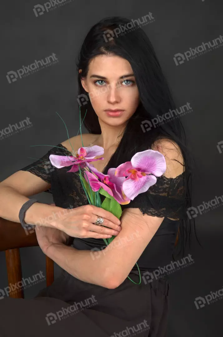 Elegant Woman with Striking Blue Eyes Holding Pink Orchid Flowers