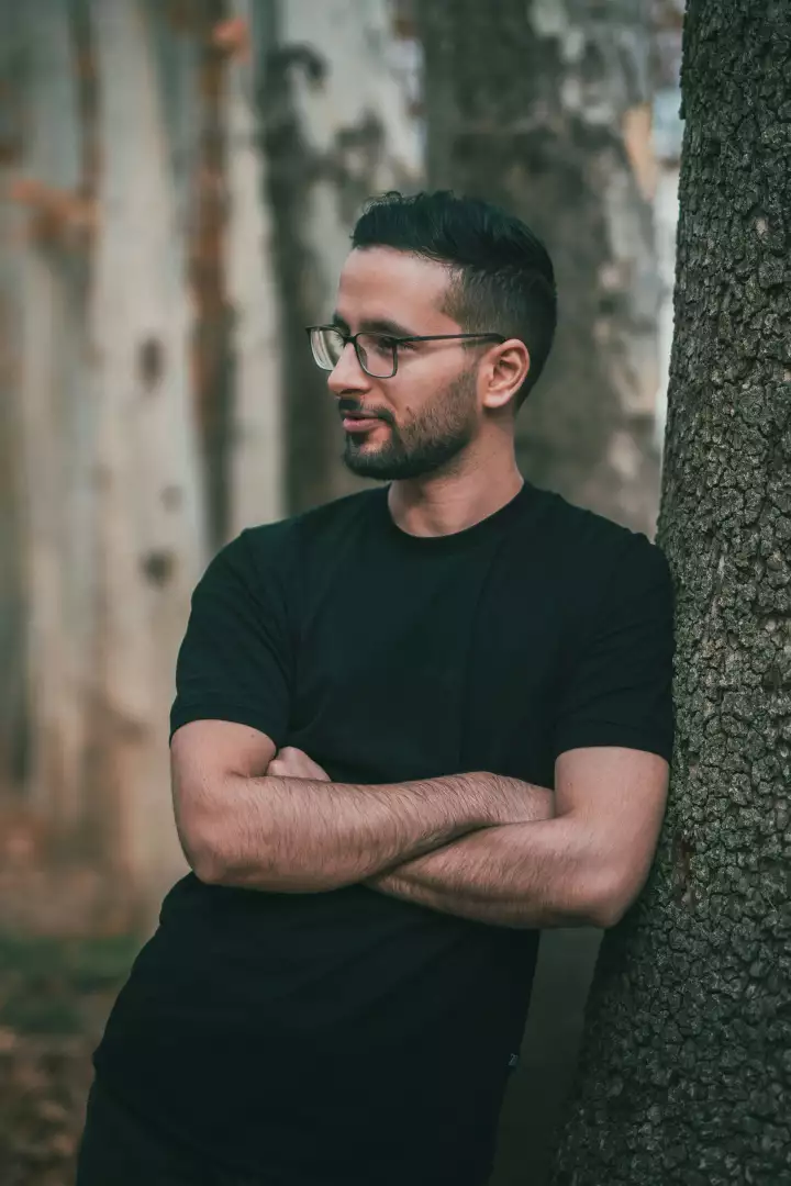 Free Premium Stock Photos Man Wearing Glasses Leans Against Tree Trunk, Arms Crossed, Looking Away