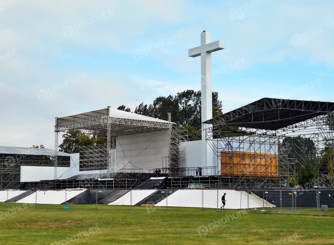 Large Outdoor Event Stage and Towering White Cross Under Construction