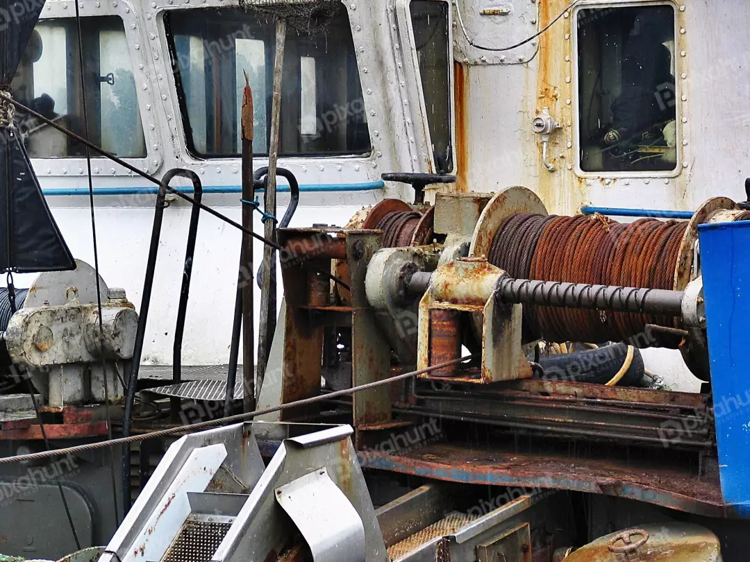 Detailed Close-up of Rusty Industrial Winches and Cables on Weathered Fishing Boat