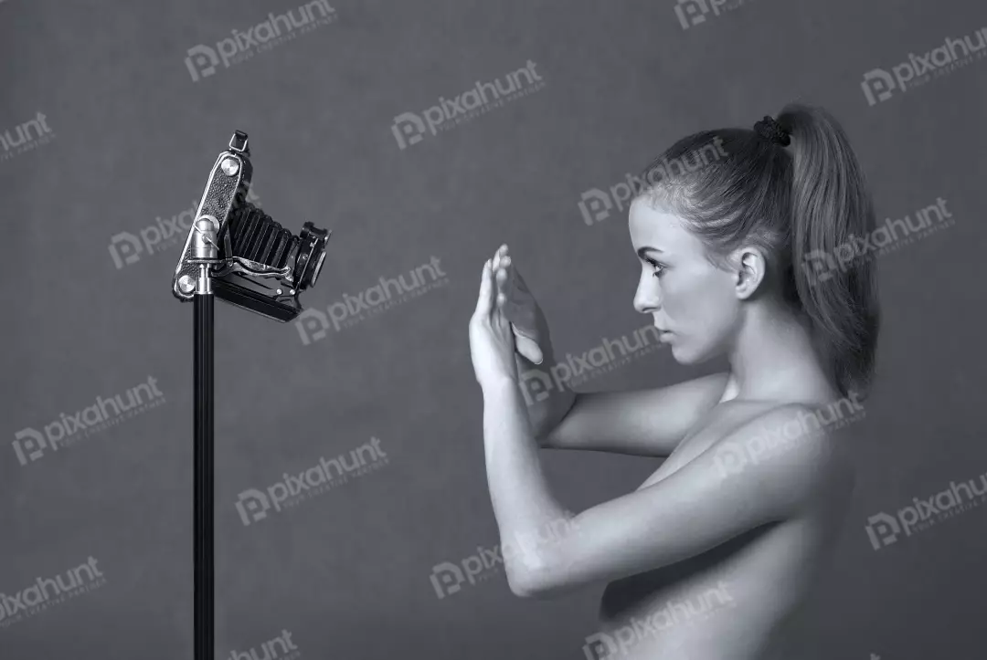 Young Woman Interacting with Vintage Folding Camera in Artistic Studio Portrait