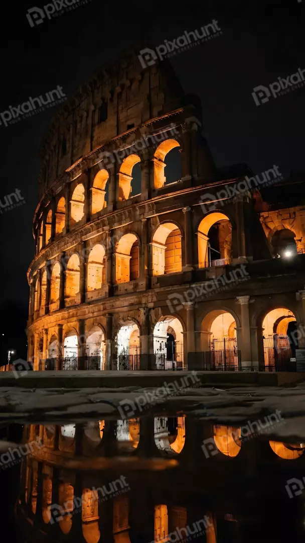 Free Premium Stock Photos Colosseum at Night Illuminated by Warm Orange Light with Reflection