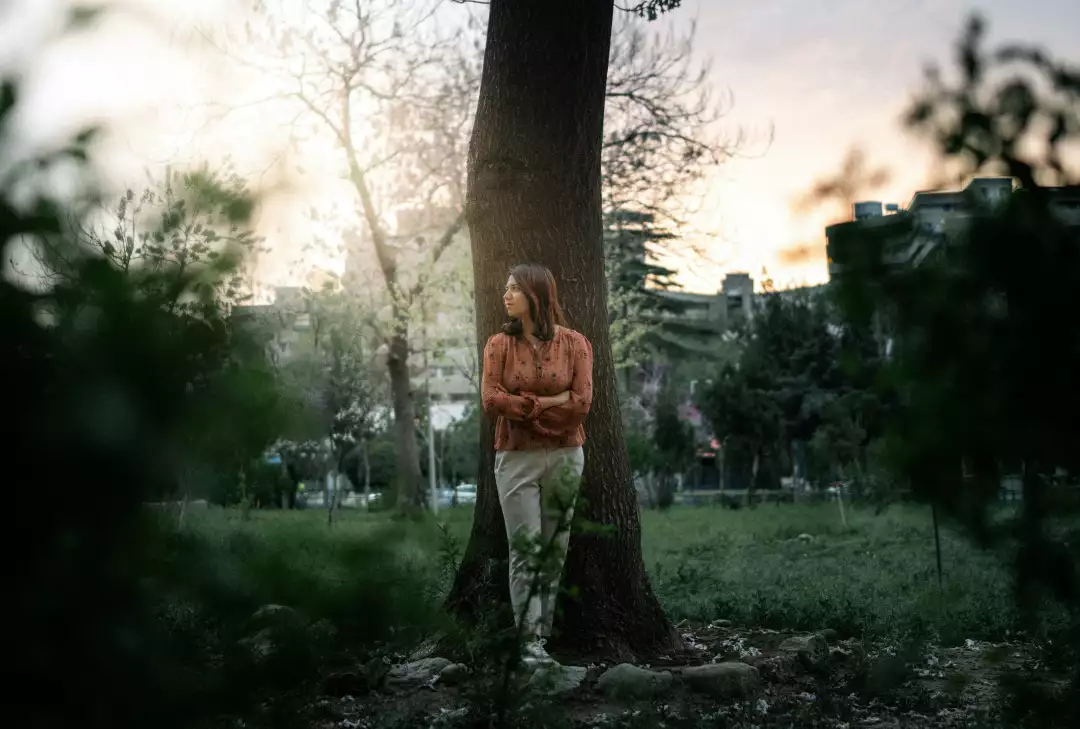 Free Premium Stock Photos Woman Posing Confidently by a Tree in a Park During Sunset