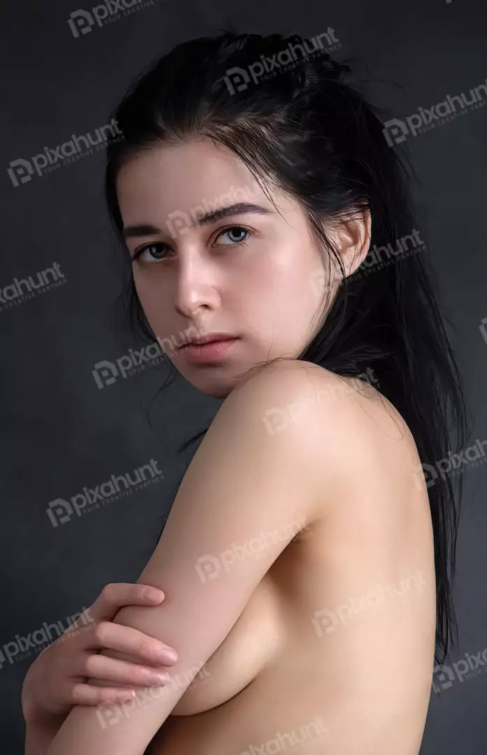 Captivating Young Woman with Dark Hair Posing Bare-chested, Arms Crossed, in Studio