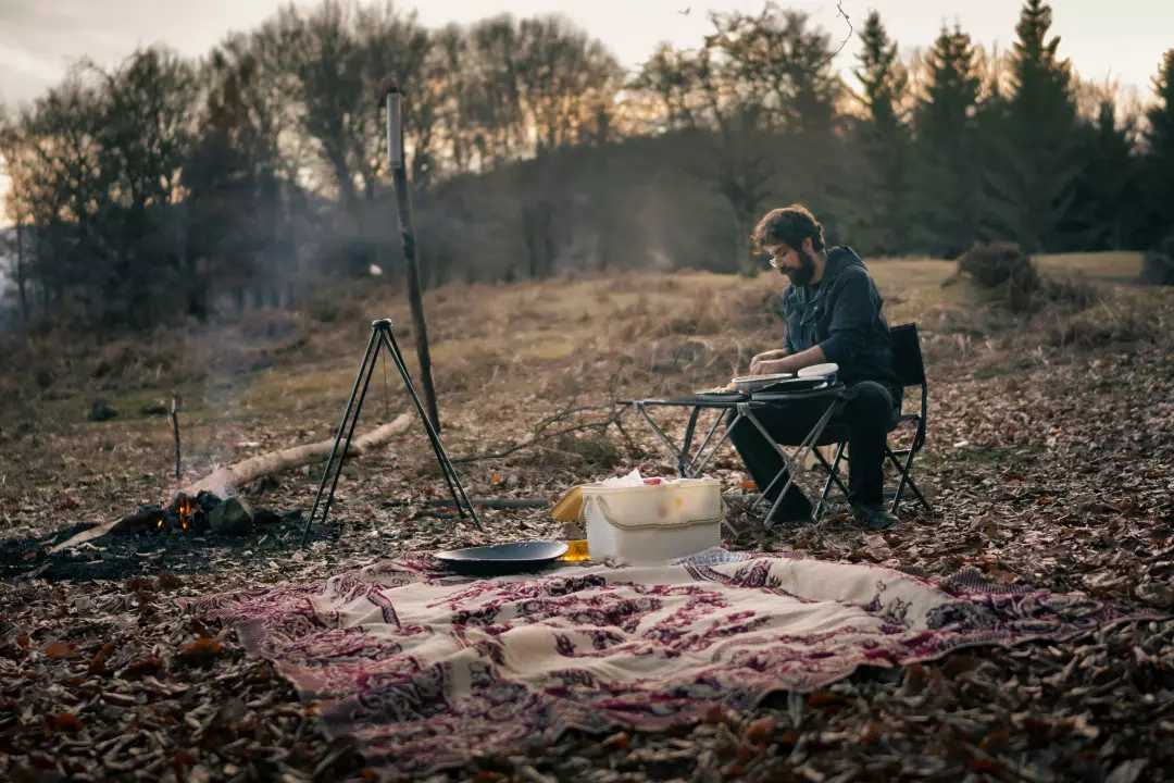 Free Premium Stock Photos Solo Traveler Prepares Outdoor Dinner Over Campfire in Rustic Wilderness at Dusk