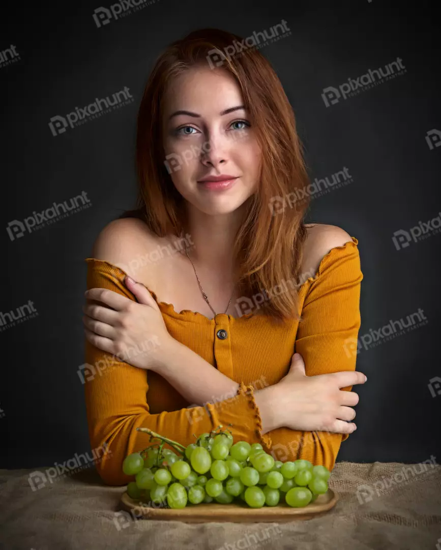 Young Woman Posing with Fresh Green Grapes in Yellow Off-Shoulder Top
