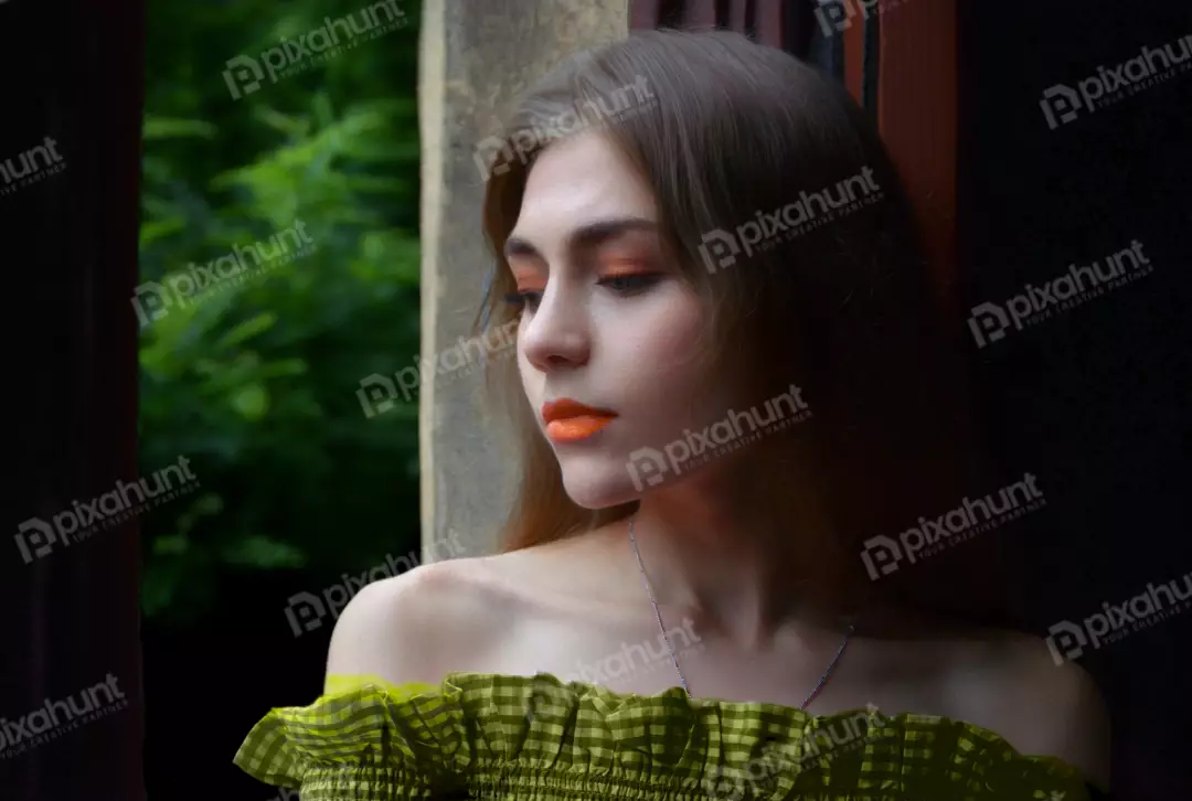 Pensive Young Woman with Orange Makeup and Gingham Top by Window