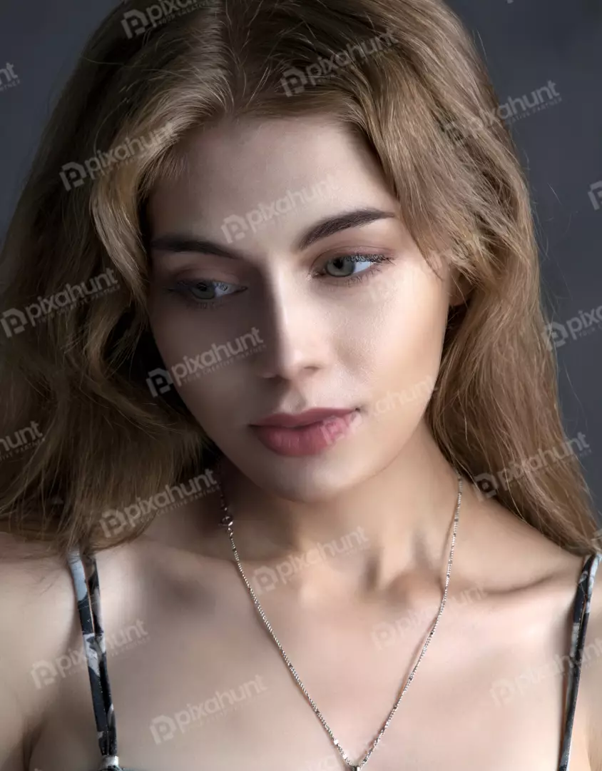 Pensive Young Woman with Long Wavy Hair and Delicate Silver Chain Necklace